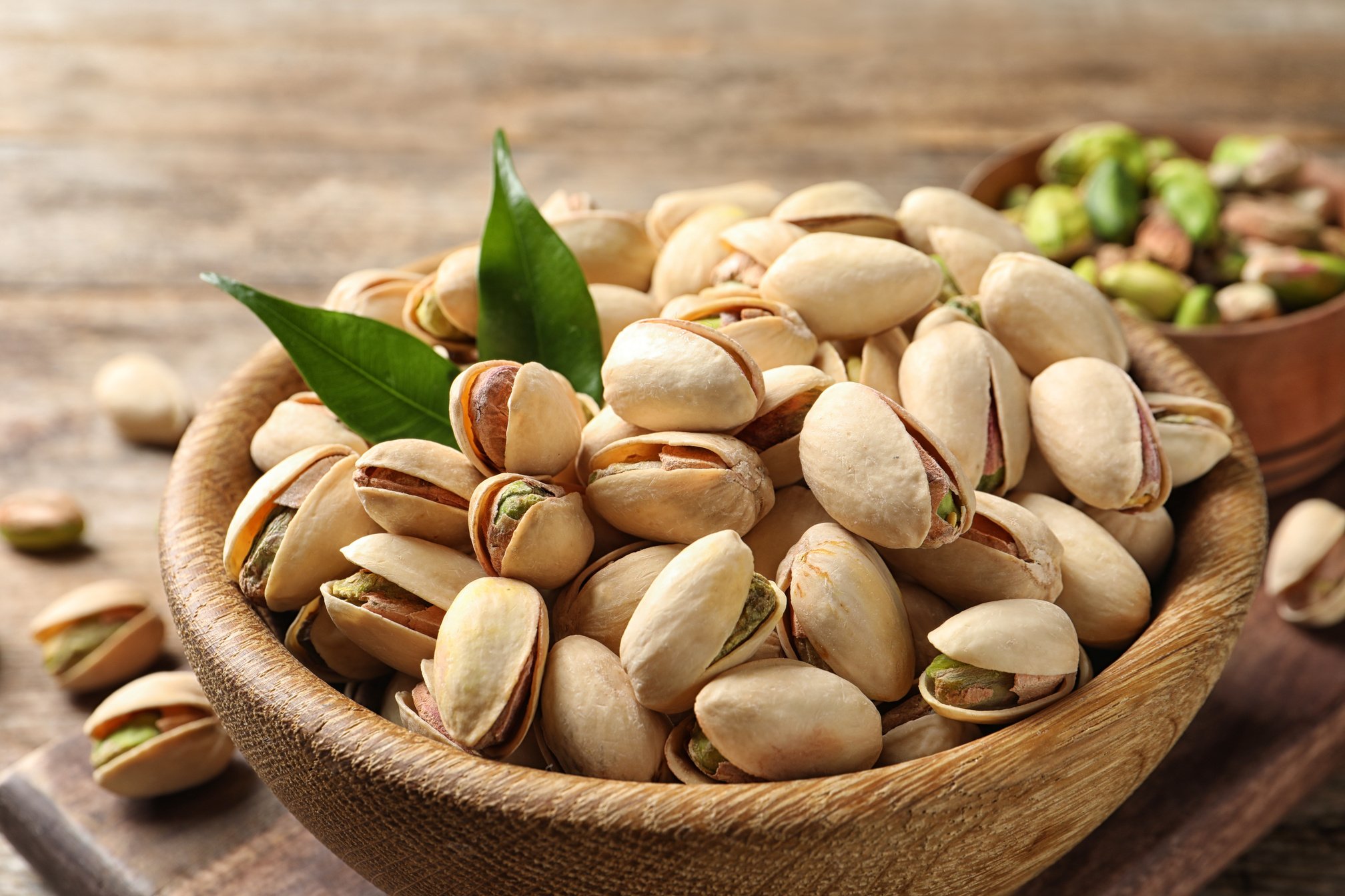 Organic Pistachio Nuts in Bowl on Wooden Table, Closeup